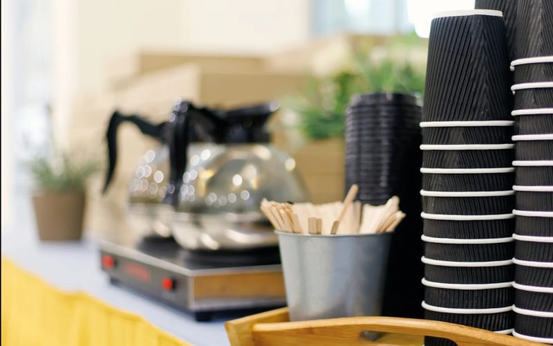 Beverage station with syrup bottles, cups, and lids